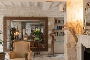 A cozy room with a stone wall, a large mirror, a fireplace, and a bookshelf.