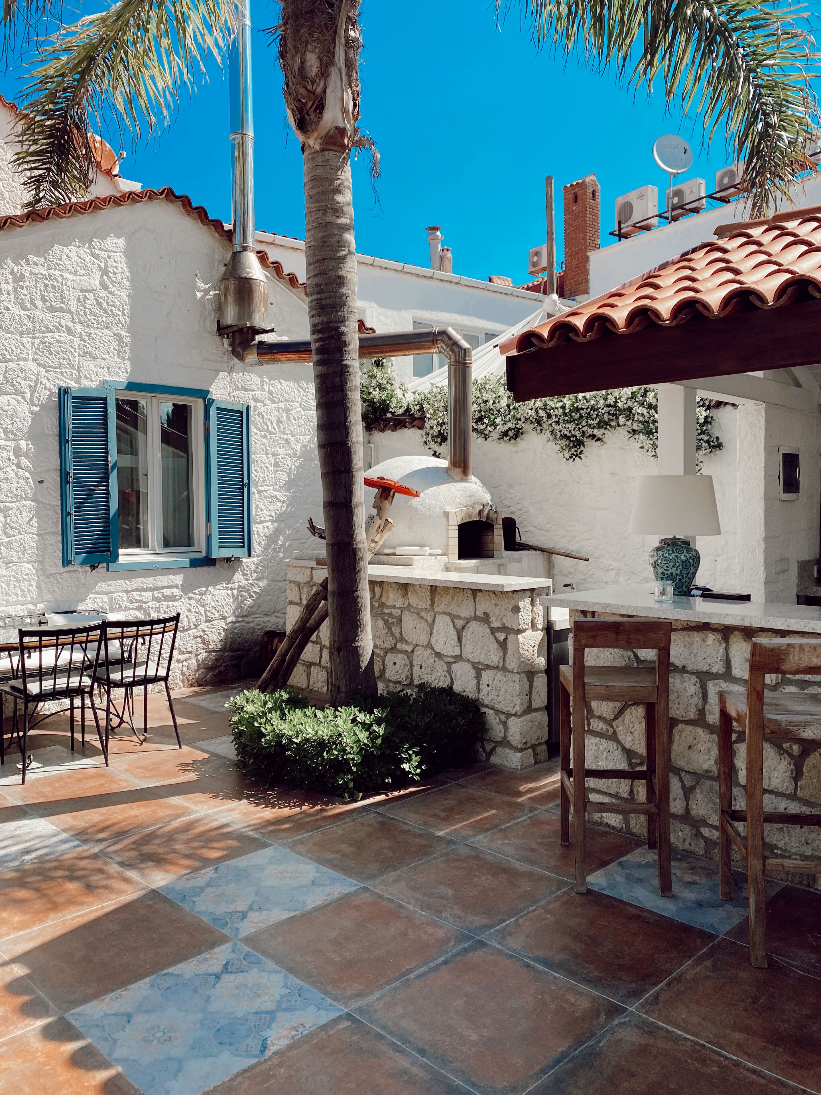 A patio area with stone flooring, a wooden table, and chairs.
