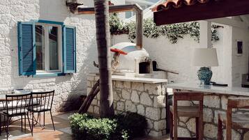 A patio area with stone flooring, a wooden table, and chairs.