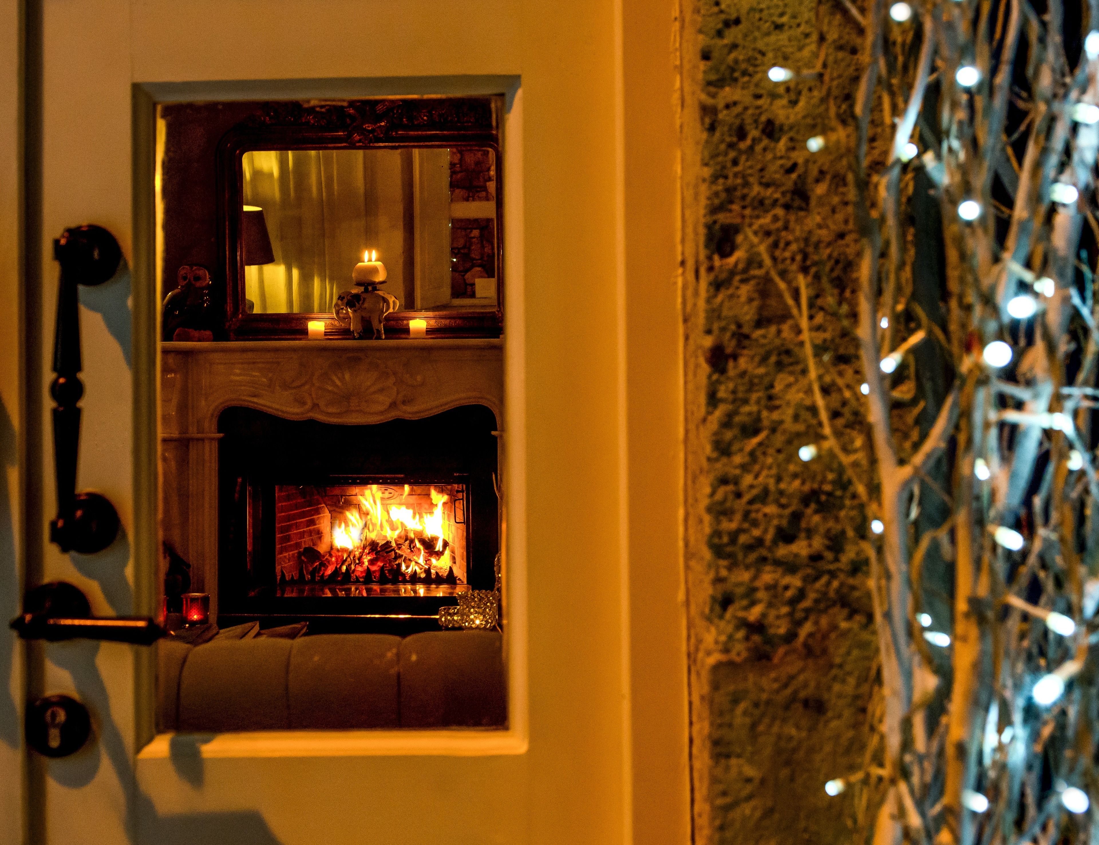 A fireplace with a lit fire, a mirror above it, and a door with a keyhole.