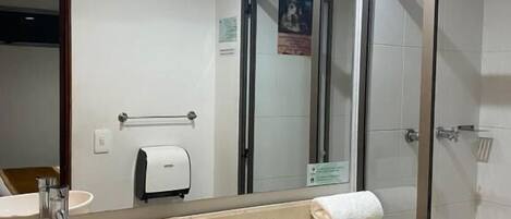 Un baño con un espejo grande, un lavabo, un inodoro y una zona de ducha.