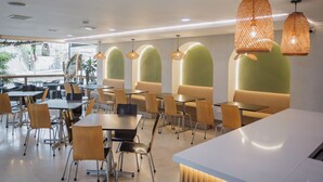 A modern restaurant interior with tables, chairs, and hanging pendant lights. - Hotel Portón Sabaneta (Sabaneta)