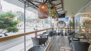 An outdoor seating area with wicker furniture, a decorative hanging light, and a view of the street. - Hotel Portón Sabaneta (Sabaneta)