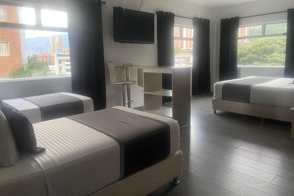 A hotel room with two beds, a TV mounted on the wall, and a desk with a chair.