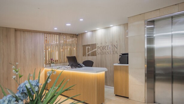 A hotel reception desk with a modern design, a reception area, and an elevator. - Hotel Portón Sabaneta (Sabaneta)