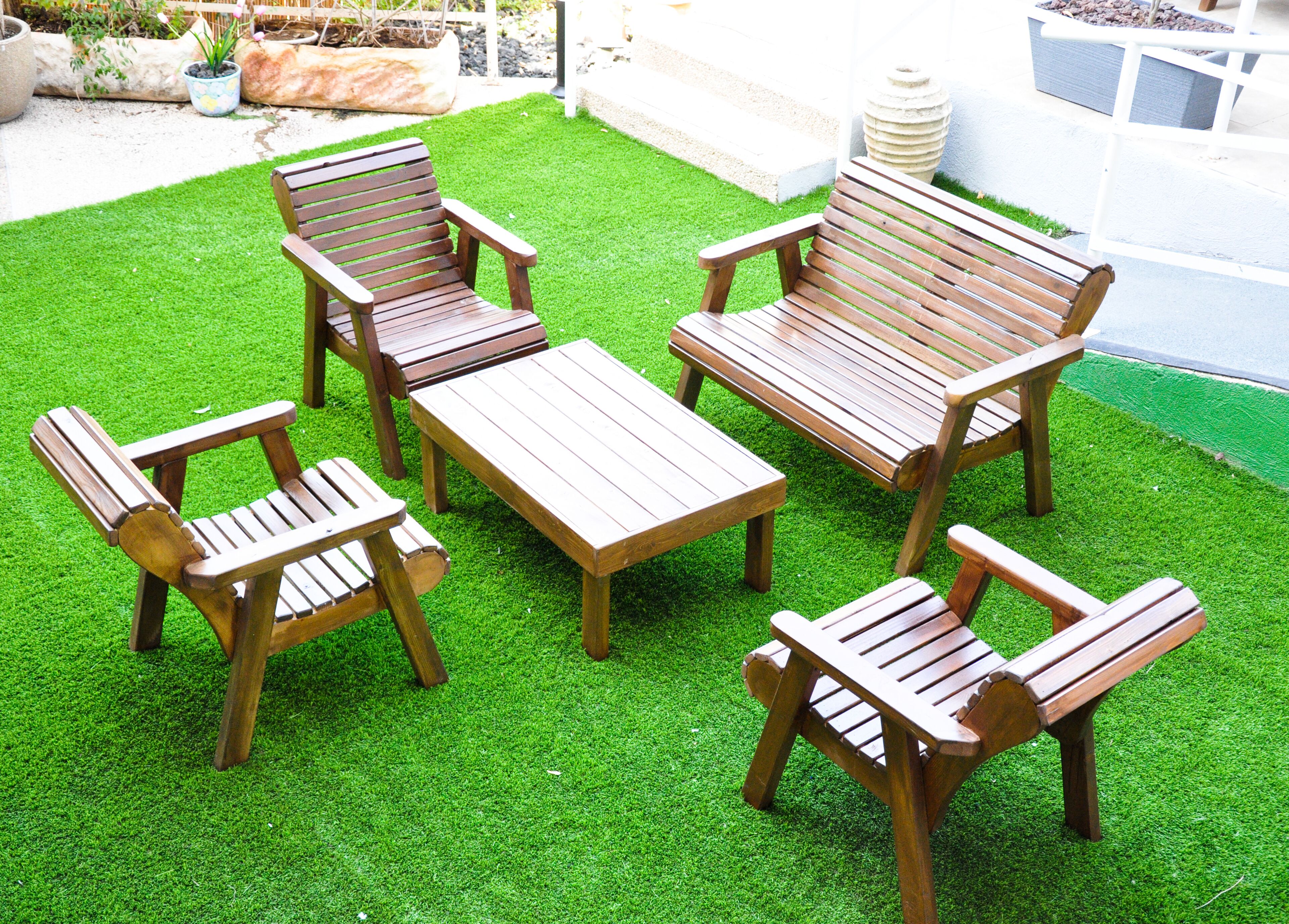 Een terras met houten meubels, waaronder een tafel en vier stoelen.
