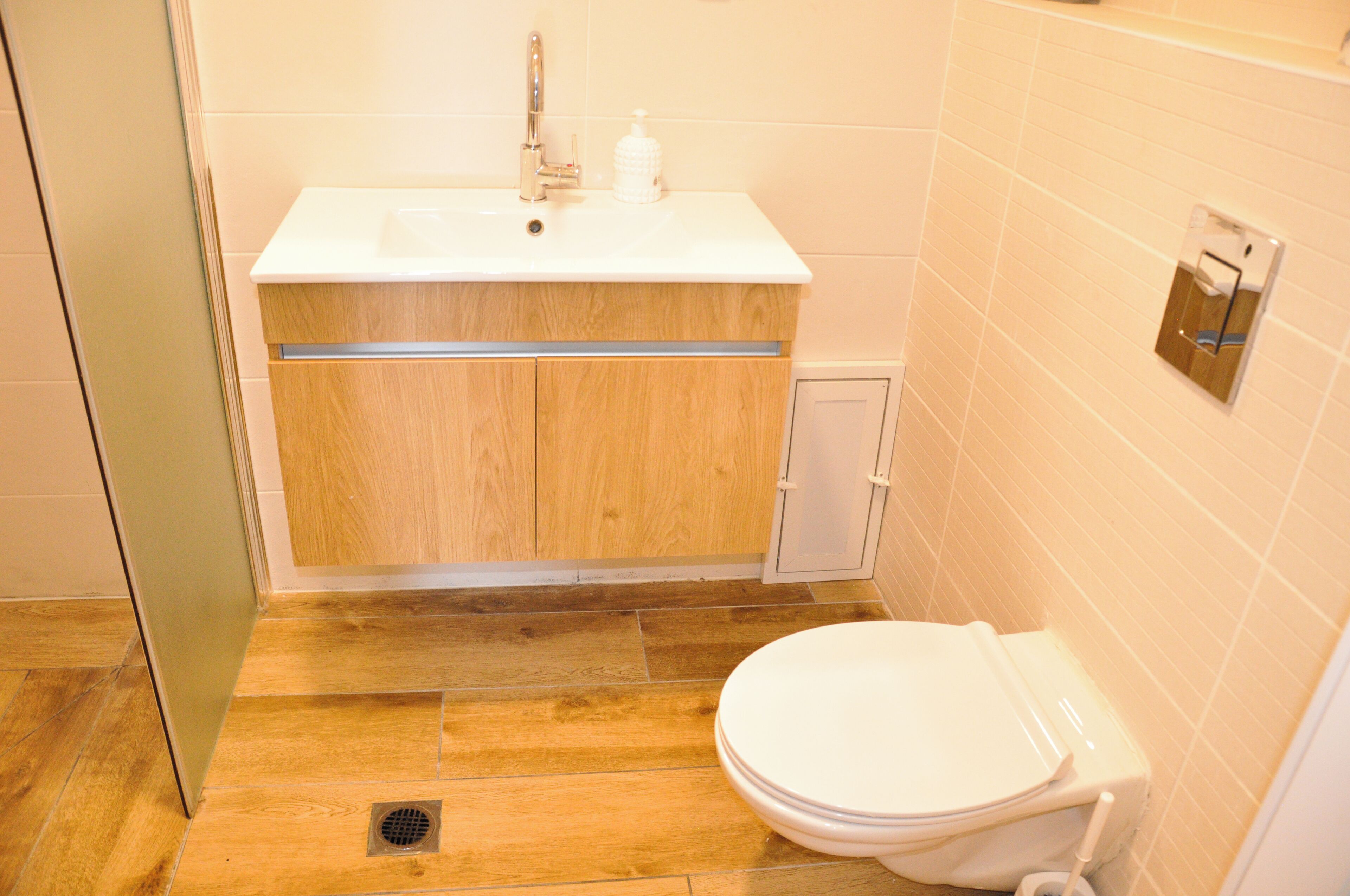 Un baño con lavamanos blanco, mueble de madera y un inodoro.