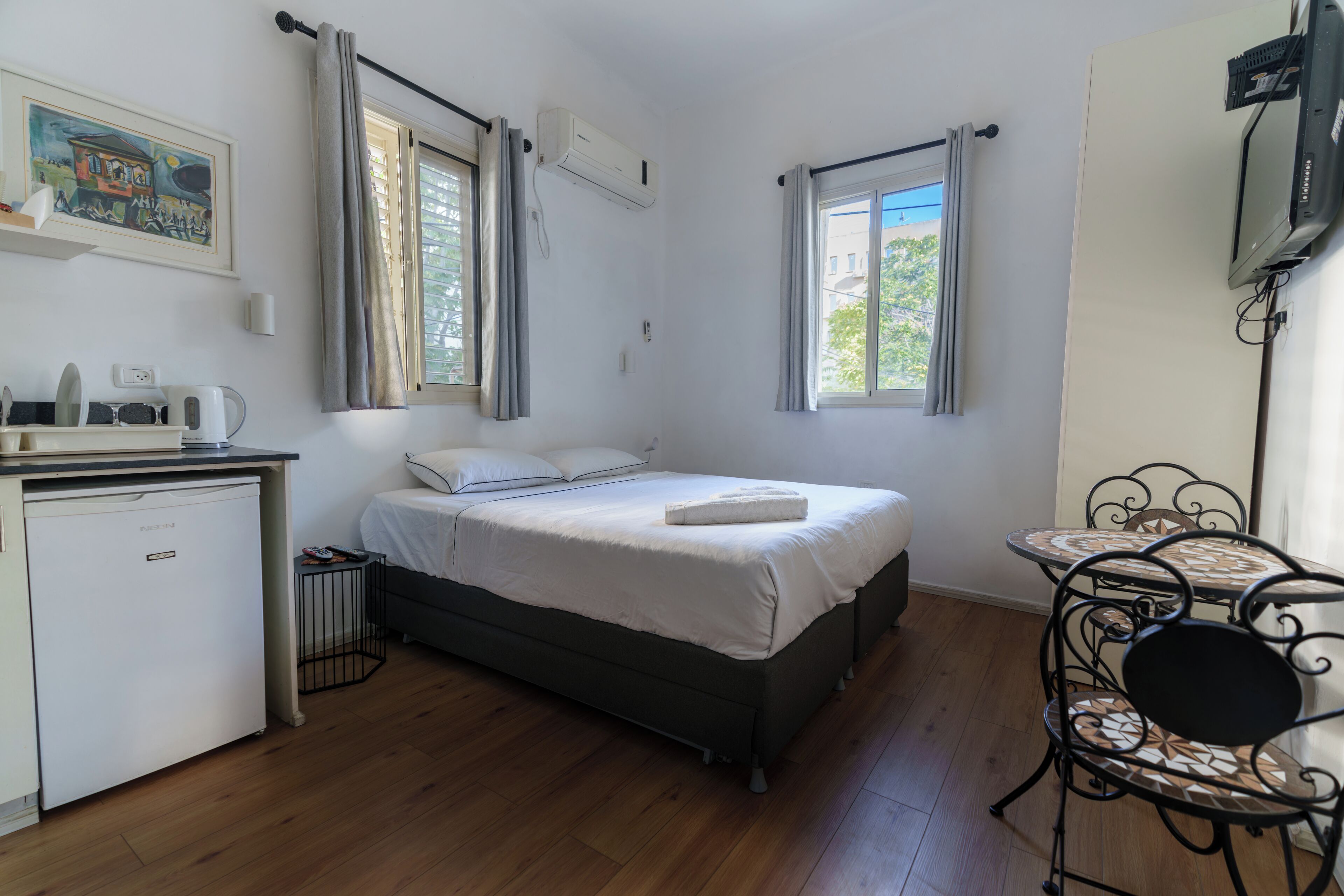 Un dormitorio con cama, mesita de noche y una pequeña escritorio con refrigerador.