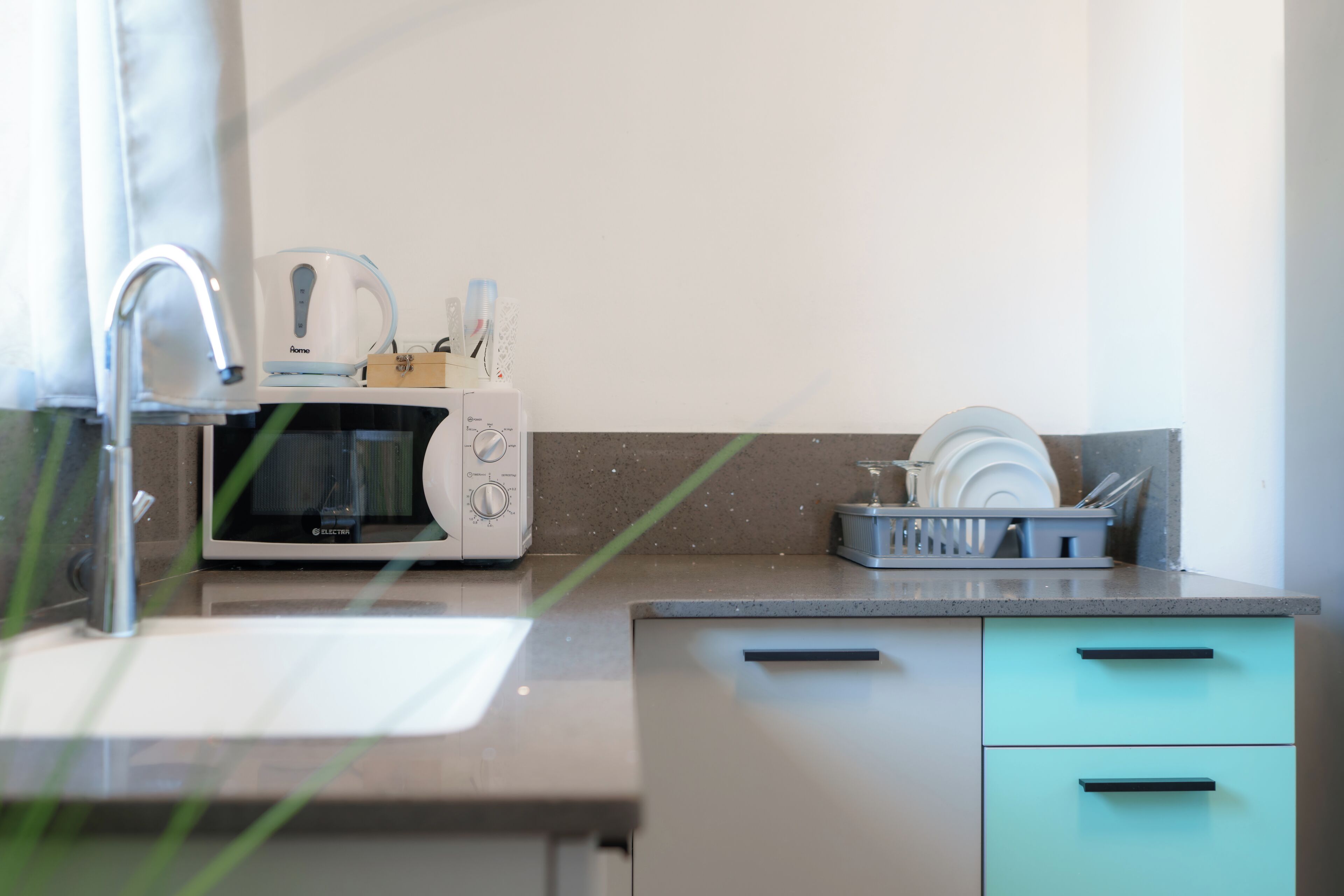 Una cocina moderna con microondas, tostadora y escurreplatos.