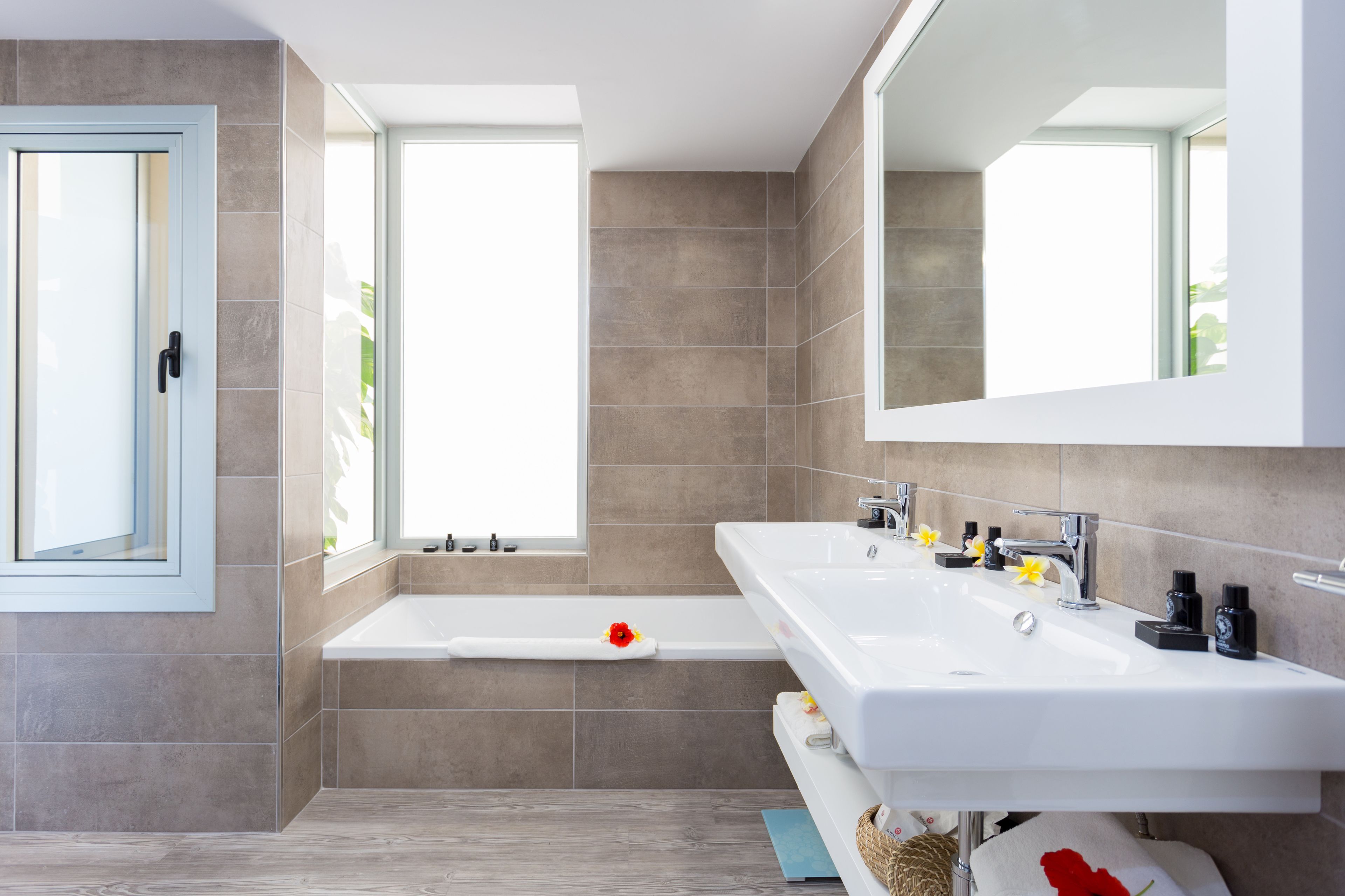 A modern bathroom with a bathtub, a large mirror, and a vanity with a sink.
