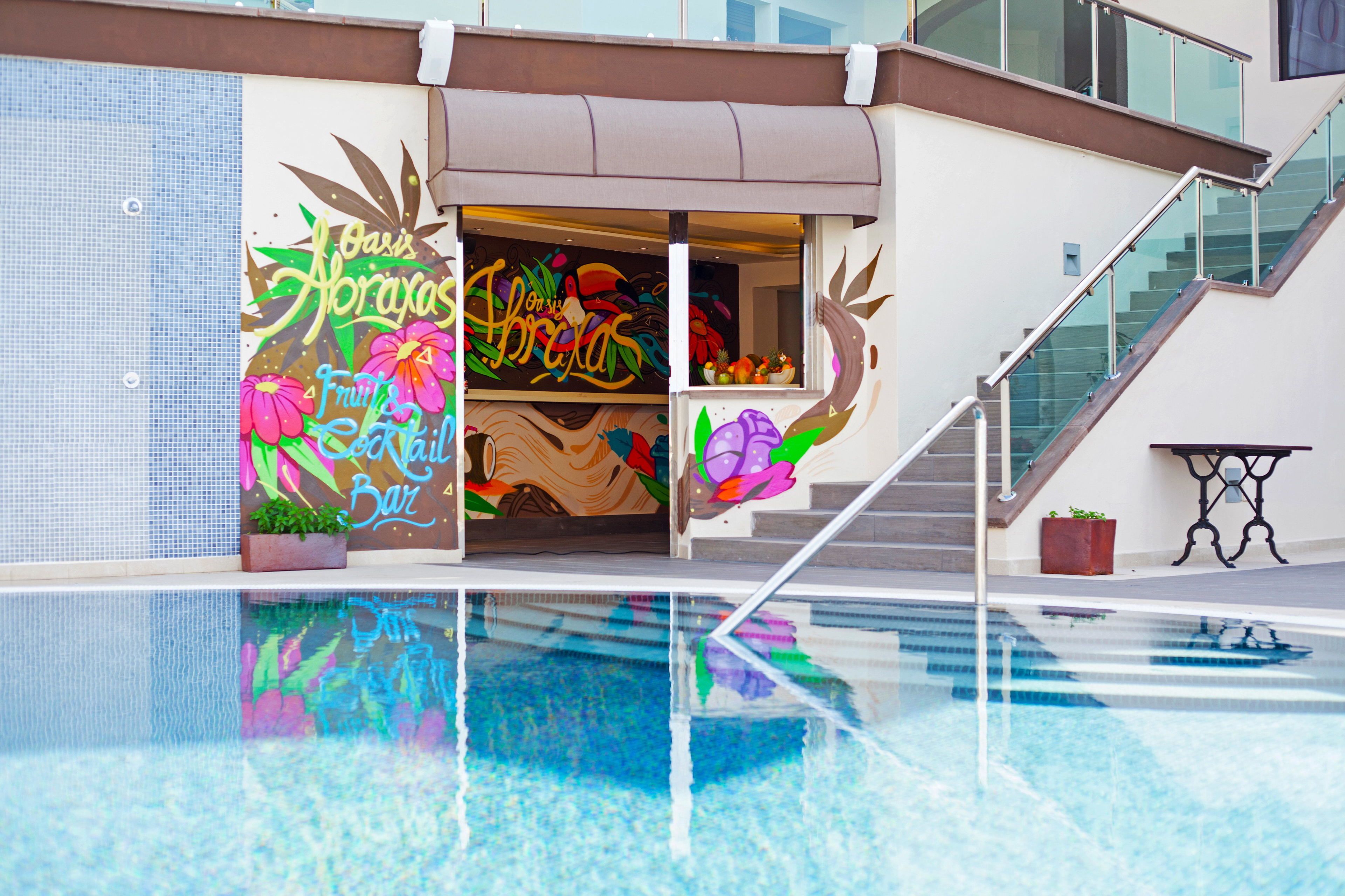 A modern building with a pool, a staircase, and a colorful mural on the wall.