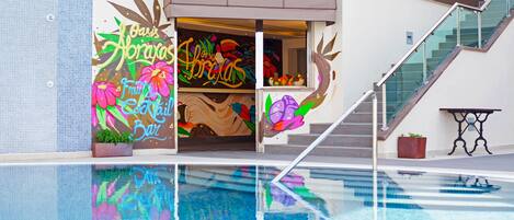 A modern building with a pool, a staircase, and a colorful mural on the wall.