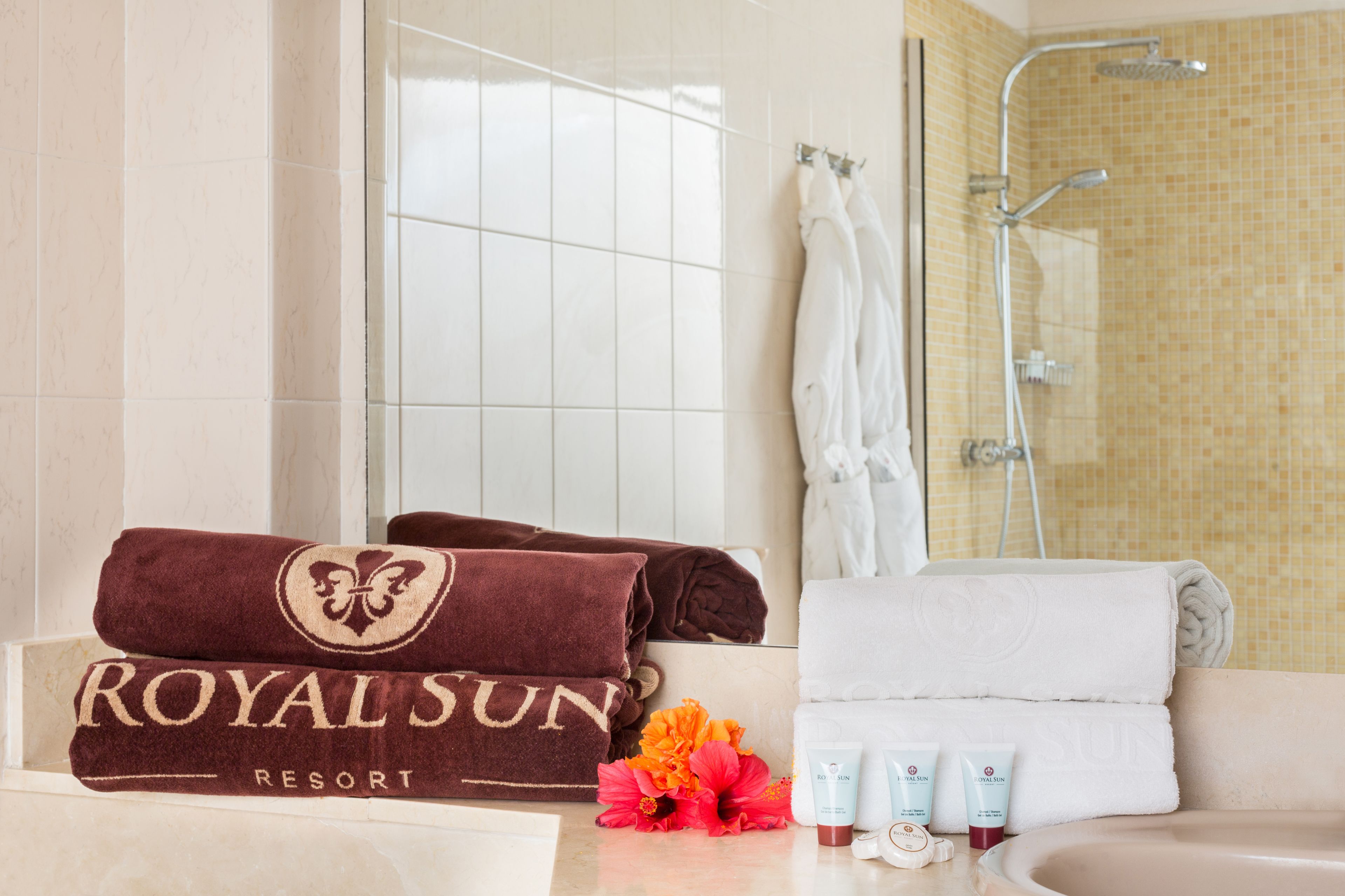 Un baño con bañera, ducha y lavamanos. Hay toallas y artículos de aseo en el mostrador.