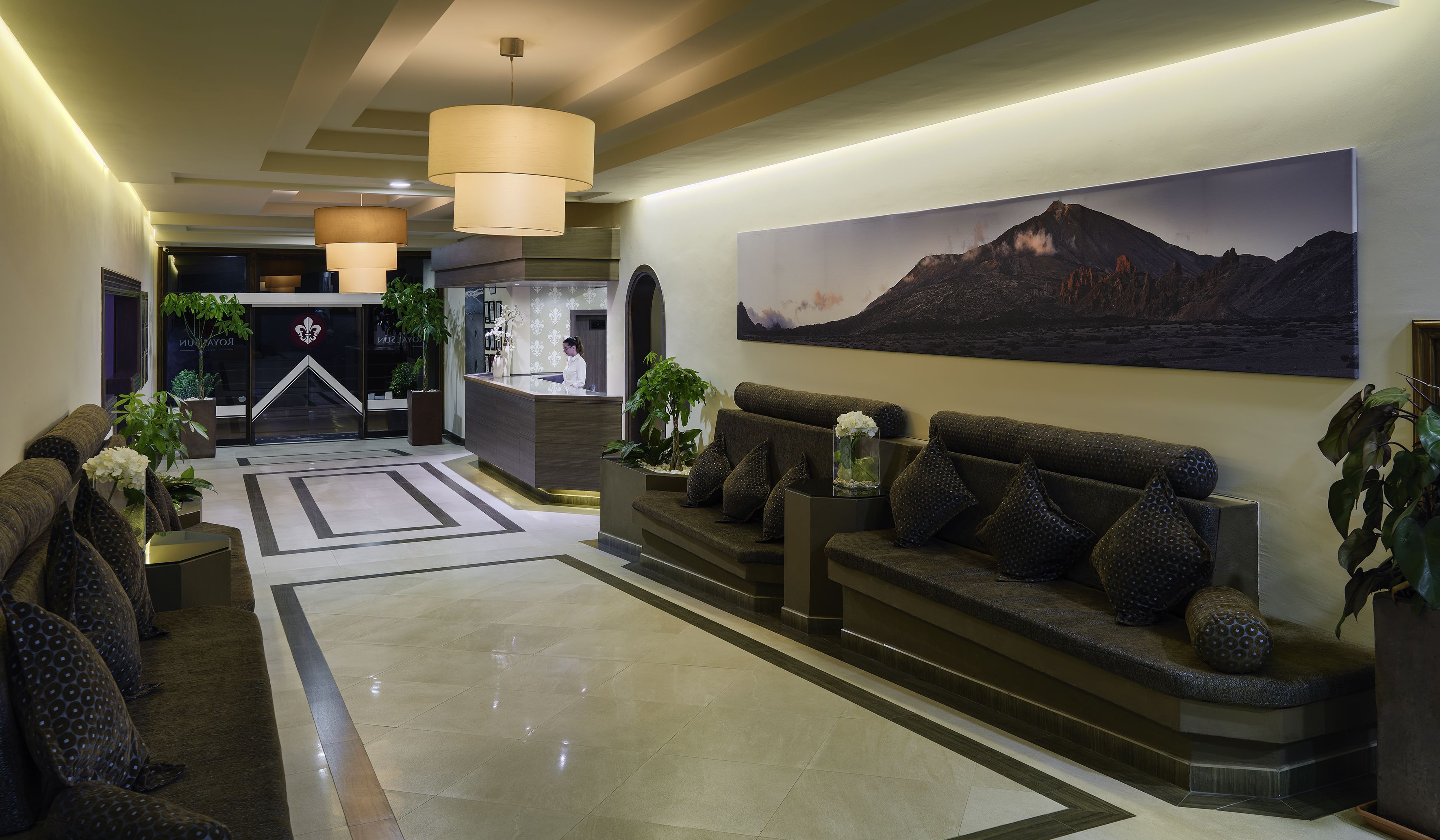 Eine moderne Lobby mit einer Rezeption, einem großen Gemälde von einem Berg und einer Sitzecke mit gemusterten Kissen.