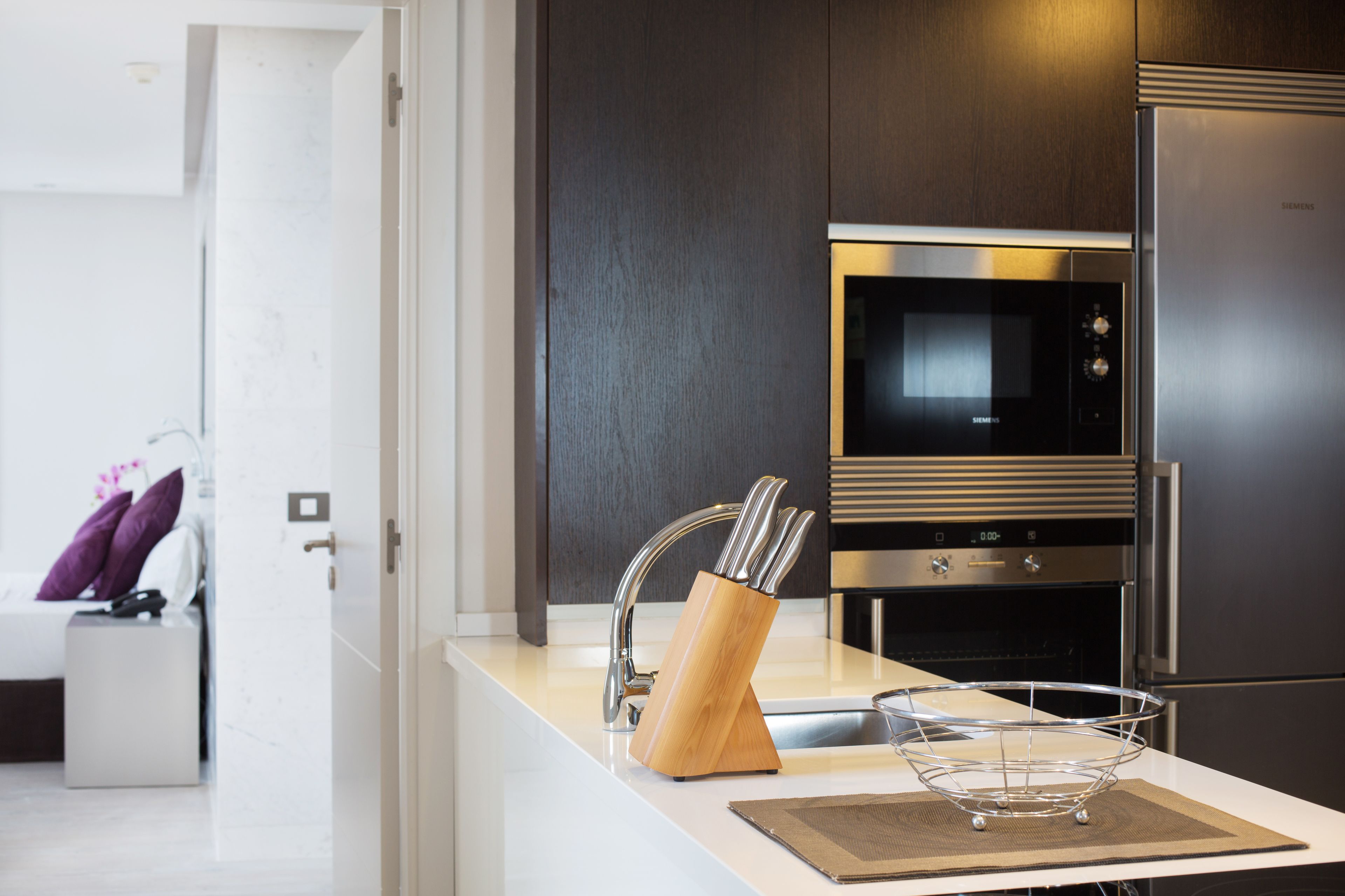 A modern kitchen with a stainless steel refrigerator, a built-in oven, and a microwave.