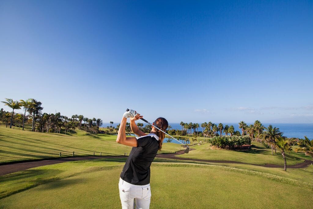 Un campo de golf con vista despejada al océano y palmeras.