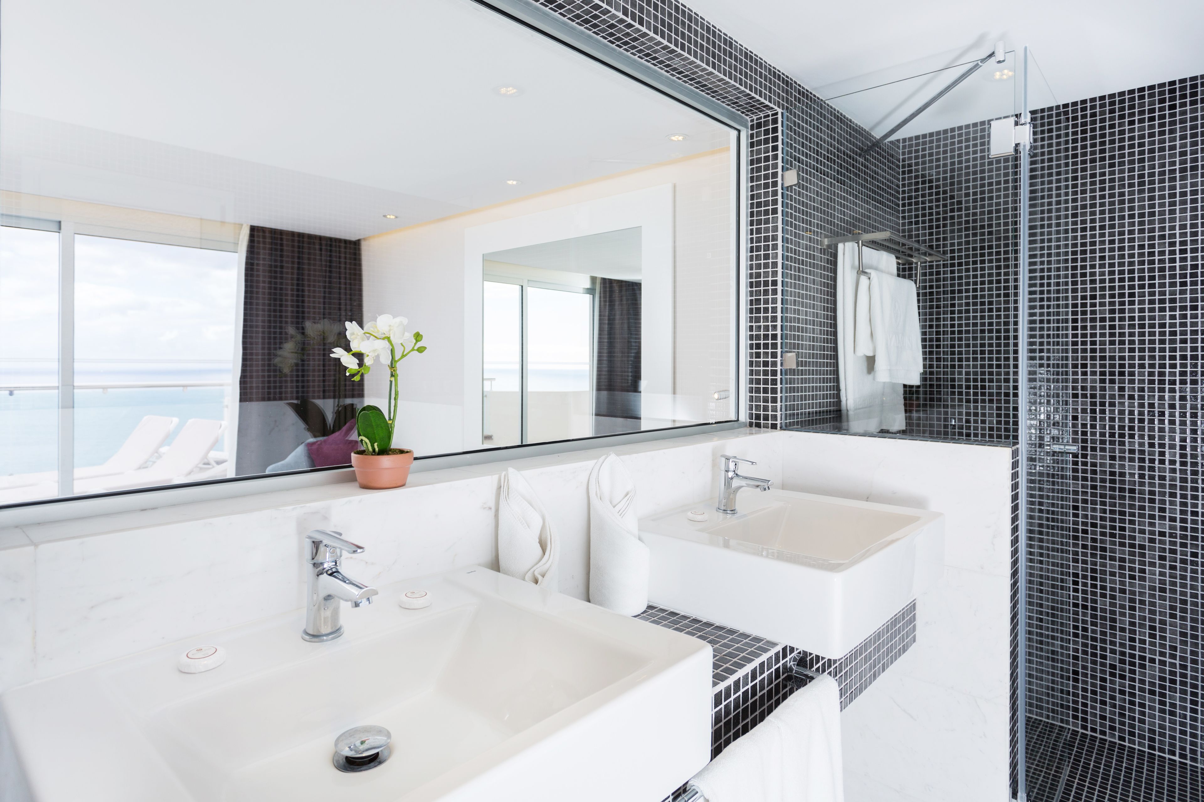 Une salle de bain moderne avec deux lavabos, un grand miroir et un espace douche.