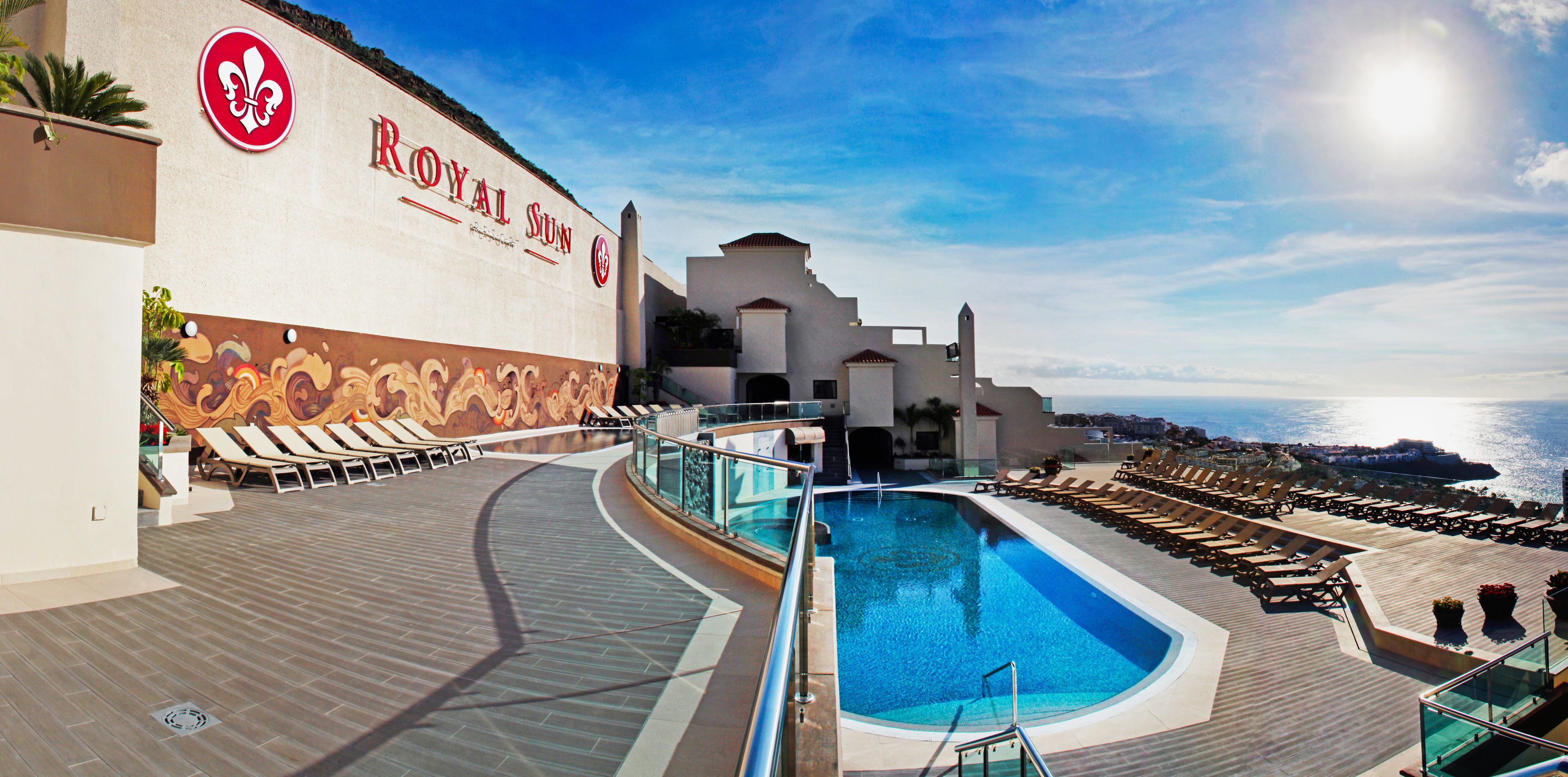 Zona de piscina con sillones de descanso y vista al mar.