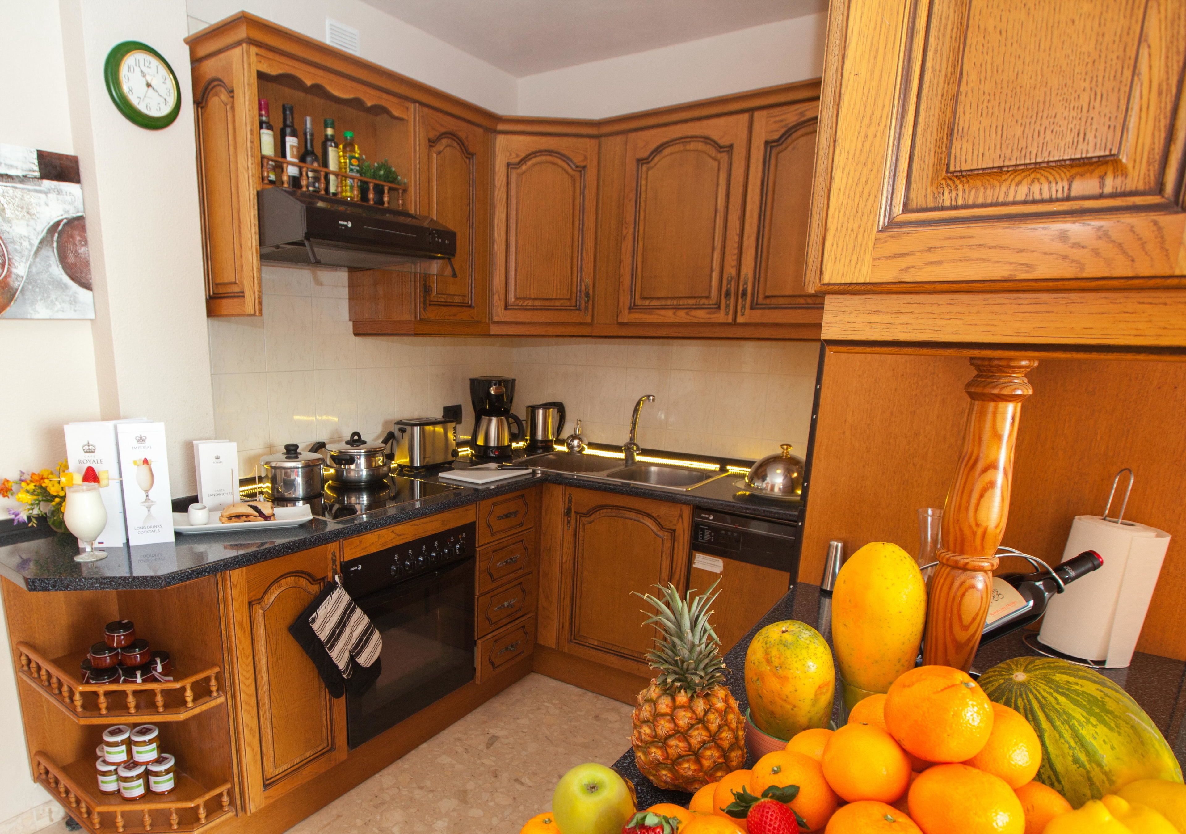 Una cocina con armarios de madera, encimera negra y varios electrodomésticos.