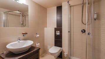 A modern bathroom with a large sink, a toilet, and a glass-enclosed shower.