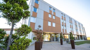 Een modern hotel met een platte gevel, grote ramen en een centrale ingang met glazen deuren.
