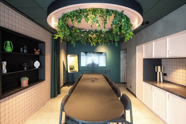 Una cocina moderna con una mesa larga, armarios oscuros y un jardín vertical.