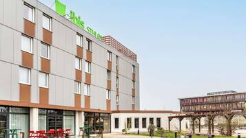 A modern hotel with a flat facade, large windows, and a green logo.