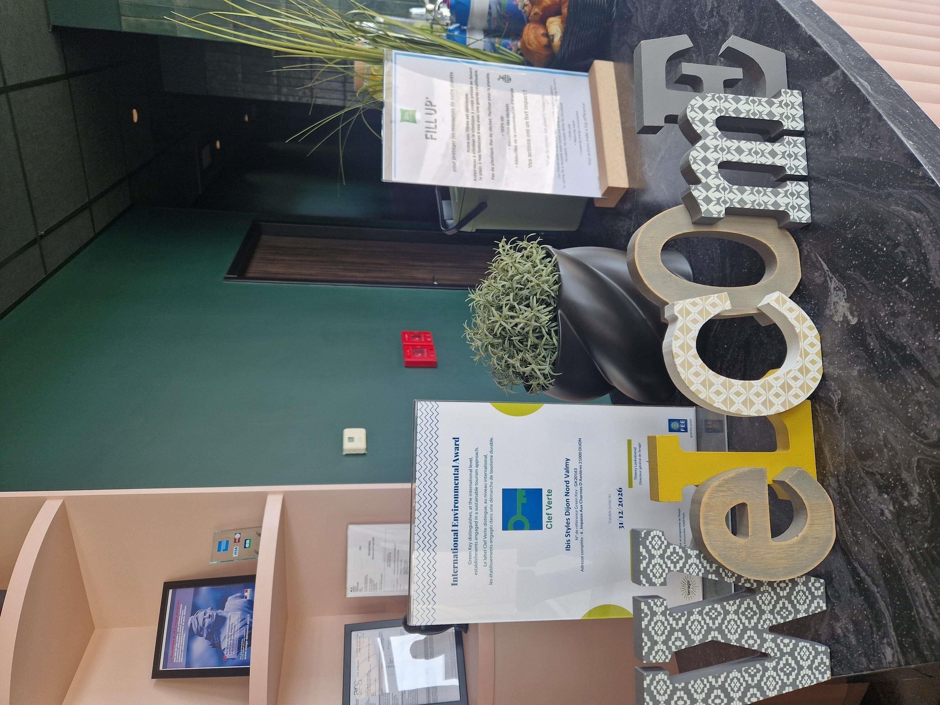 A reception desk with a 'Welcome' sign, a plant, and documents on the counter.