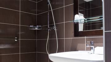 Un baño moderno con ducha, lavamanos y espejo.
