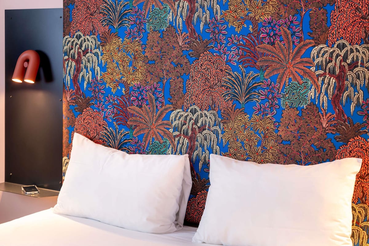 A bed with white pillows and a colorful, patterned headboard.