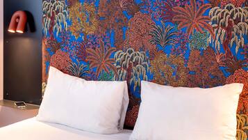 Una cama con almohadas blancas y un cabecero colorido con diseño.
