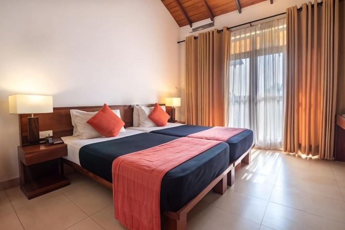 A double bed with two pillows, a nightstand, and a lamp.