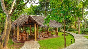 A gazebo with a thatched roof, surrounded by a paved walkway and lush greenery. - Pelwehera Village Resort (Dambulla)