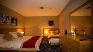 A hotel room with two beds, a dresser, a mirror, and a nightstand with a lamp.