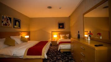 A hotel room with two beds, a dresser, a mirror, and a nightstand with a lamp.