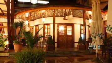 A hotel entrance with a curved facade, potted plants, and an umbrella.