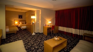 A hotel room with a bed, desk, chair, and a small table with a tray.