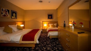 A hotel room with two beds, a dresser, a mirror, and a nightstand with a lamp.