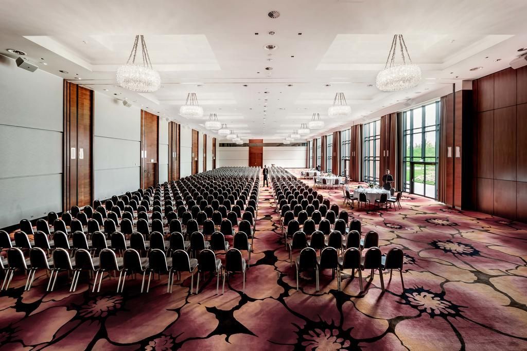 A conference room with rows of chairs, a long table, and large windows.