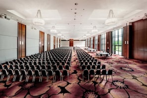 A conference room with rows of chairs, a long table, and large windows.