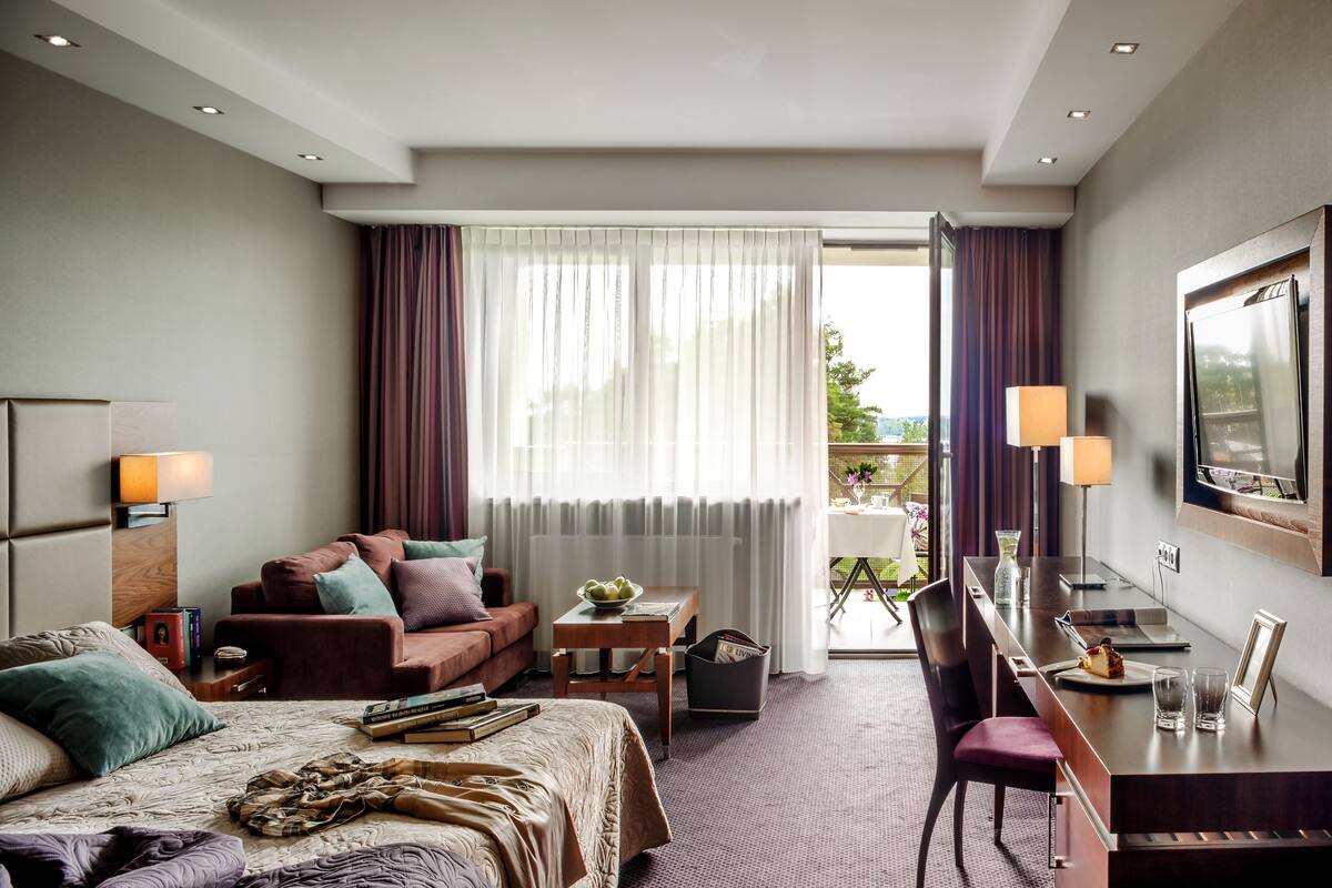 Une chambre d’hôtel avec un lit, un bureau, un canapé et une télévision.