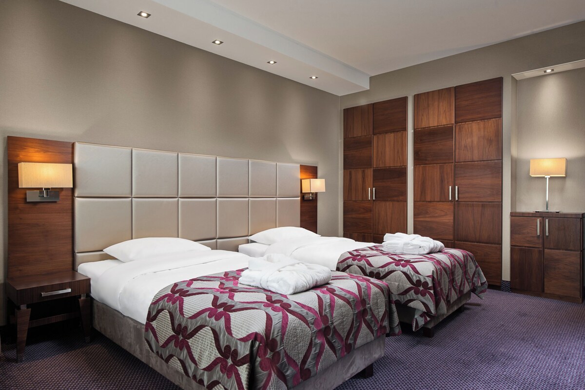 Une chambre d’hôtel avec deux lits, une grande armoire en bois et un petit bureau.