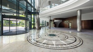 A spacious lobby with a circular mosaic floor, large glass windows, and a modern architectural design. - Hotel Warszawianka (Serock)