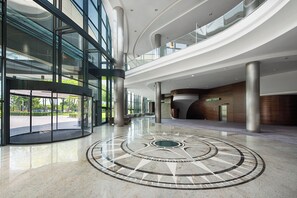 A spacious lobby with a circular mosaic floor, large glass windows, and a modern architectural design. - Hotel Warszawianka (Serock)