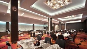 A spacious dining area with multiple tables set for service, a modern chandelier, and a carpeted floor. - Hotel Warszawianka (Serock)