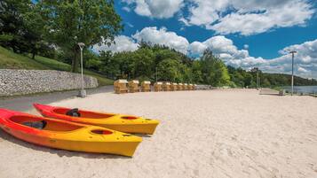 A sandy beach with kayaks and a stone wall.