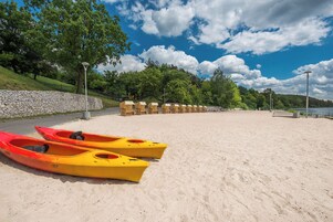 Una playa arenosa con kayaks y un muro de piedra.