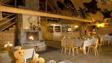 A rustic dining area with wooden furniture, a fireplace, and a bar with shelves of bottles.