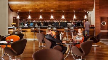 A bar area with multiple seating arrangements and a bar counter stocked with various bottles.