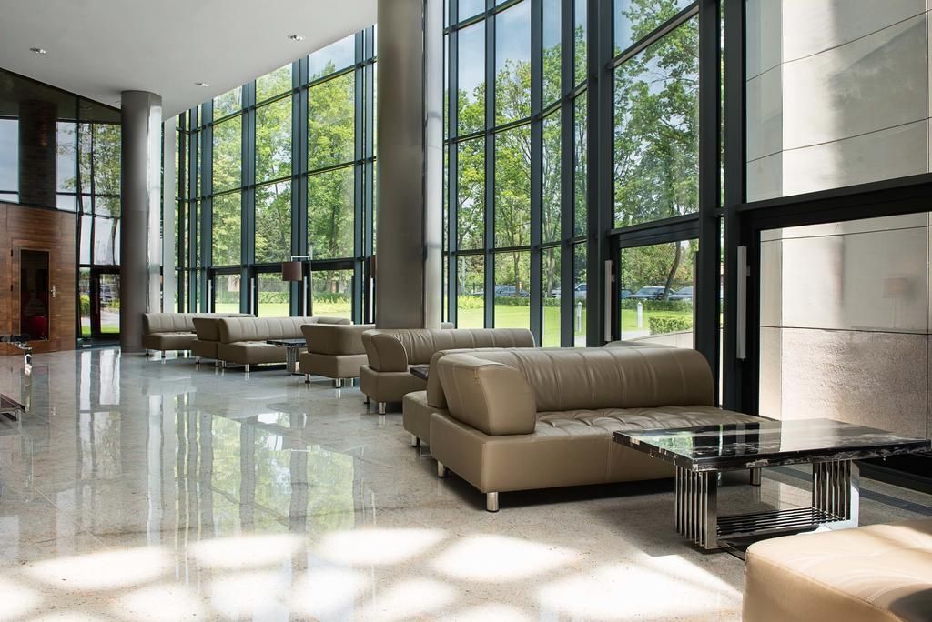 A spacious lobby with large windows, leather sofas, and a glass coffee table.
